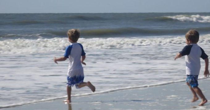 A young boy running on a beach.