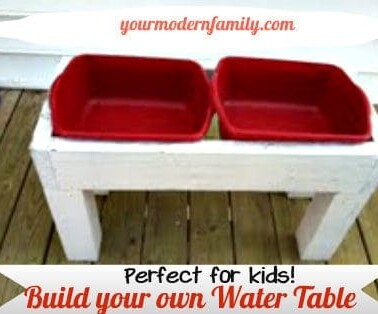 A wooden water table with two red plastic containers in it with text below it.
