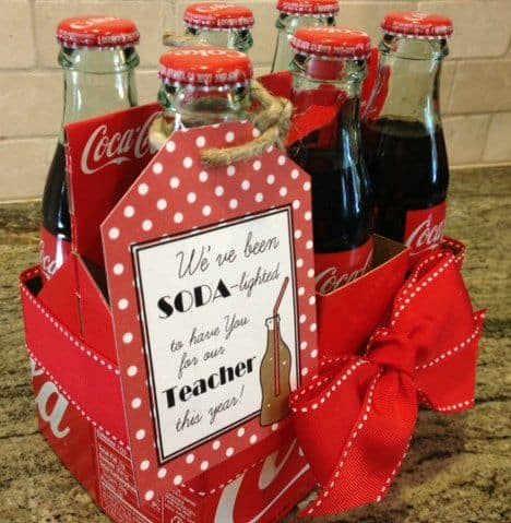 A close up of a  six pack of Coca-Cola bottles with a gift tag on them.