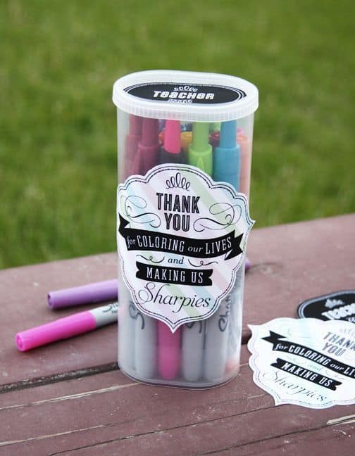 A plastic container of colored markers with a gift tag on it.
