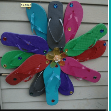 A wreath made out of flip flops hanging on a house with text below it.