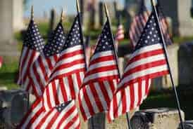 A close up of a row of American flags at a cemetery.