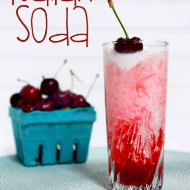 A glass of Italian soda with a container of cherries beside it.