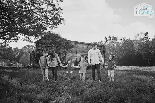 a black and white photo of a family of five walking in a field
