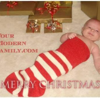 A close up of a baby in an over sized stocking with Christmas decorations around him.
