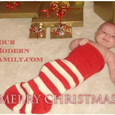 A close up of a baby in an over sized stocking with Christmas decorations around him.