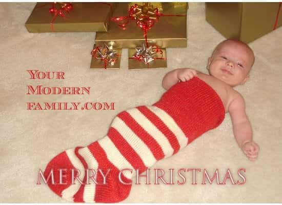 A close up of a baby in an over sized stocking with Christmas decorations around him.