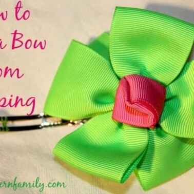 A close up of a green hair bow with a clip attached and text beside it.