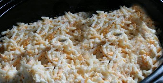 A close up of uncooked Cheesy Potato Casserole in a crock pot.