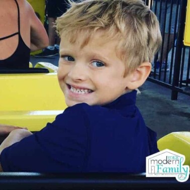 A little boy on an amusement ride smiling.
