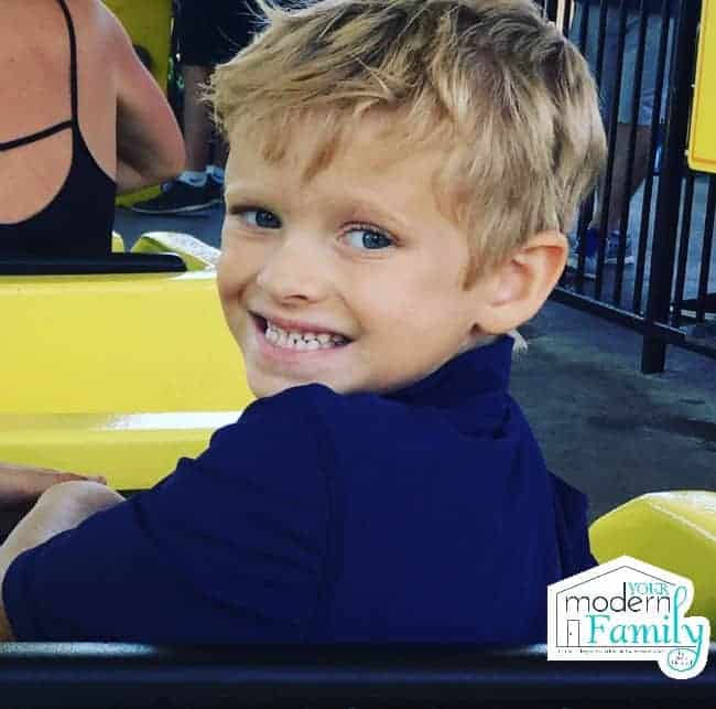 A little boy on an amusement ride smiling.