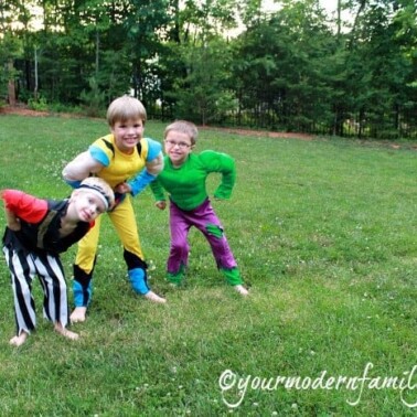 Three boys dressed up in costumes standing in a yard.
