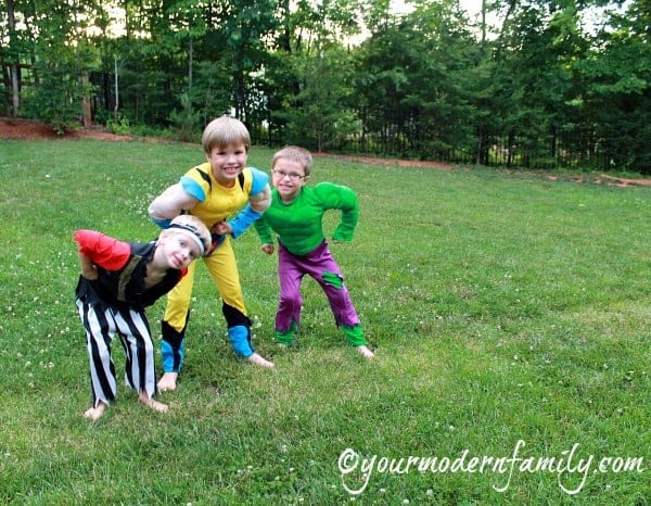 Three boys dressed up in costumes standing in a yard.
