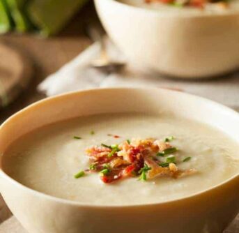A bowl of Cheesy Potato soup sitting on a table.
