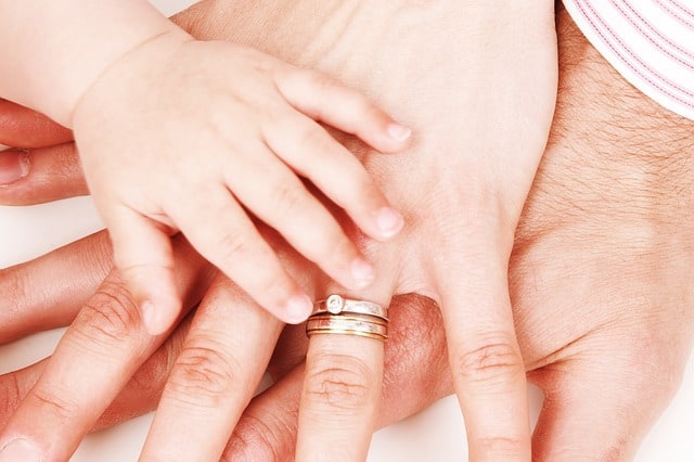 A close up of a man\'s, woman\'s and child\'s hands on top of each other.