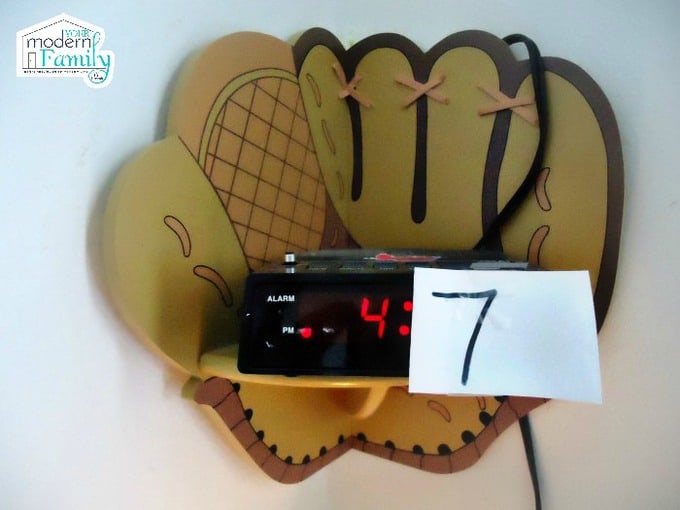 A foam baseball mitt with a clock resting against it.