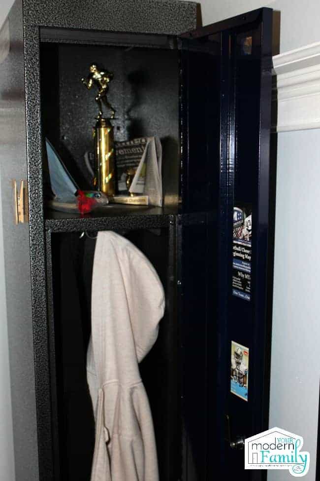 A close up of a sports locker holding a trophy and a sweatshirt.