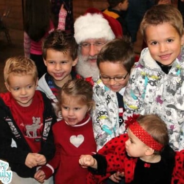 A group of young children sitting with Santa Clause.