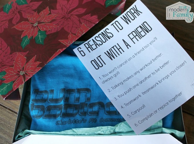 A gift box with a t-shirt in it and a sheet of paper with text on it .