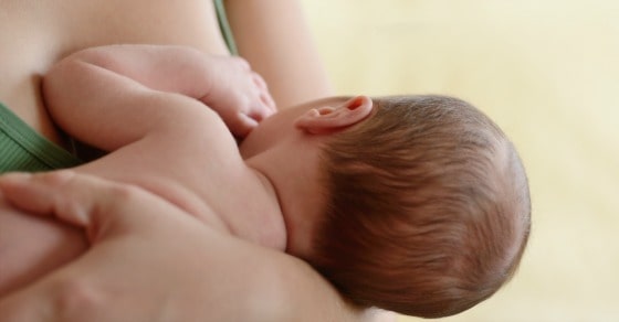 Mother holding and feeding newborn baby soft focus on the ear