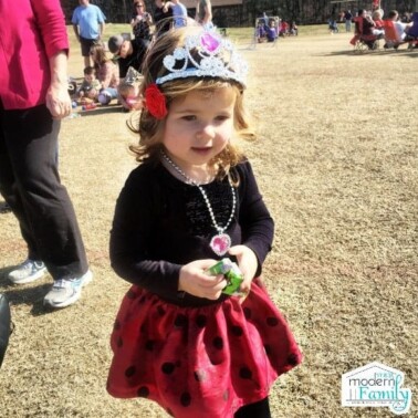 A little girl wearing a princess crown and necklace.