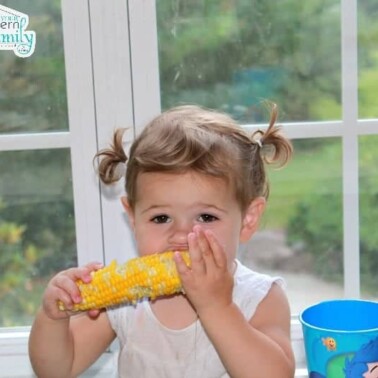 A young girl eating corn on the cob.