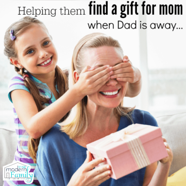 A little girl behind her mom covering her eyes while her mom holds a present with text above them.