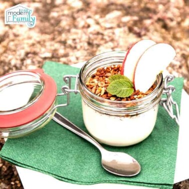 A glass mason jar with yogurt and fruit in it.