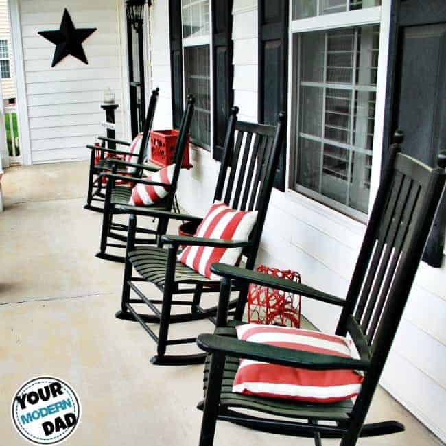 Rocking chairs on a front porch in front of a window.