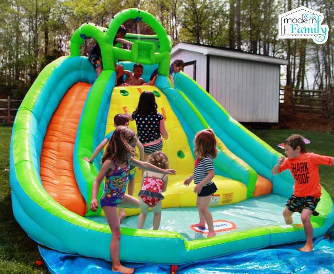 A group of kids playing on a huge blow up water slide.