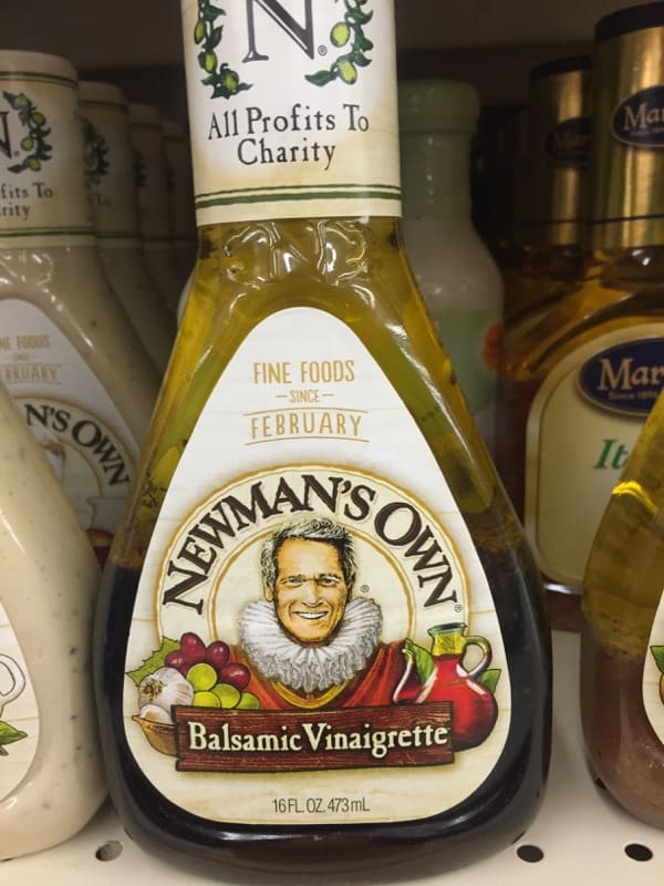 A close up of a bottle of Newmann\'s Own Balsamic Vinaigrette on a grocery store shelf.