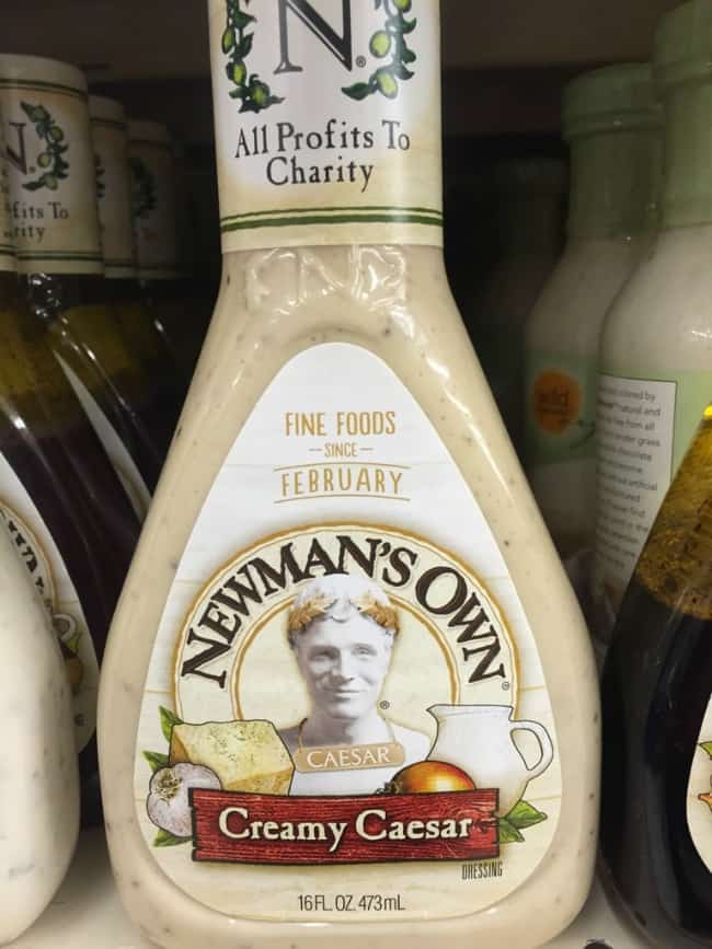A close up of a bottle of Newmann\'s Own Creamy Caesar dressing.on a grocery store shelf.