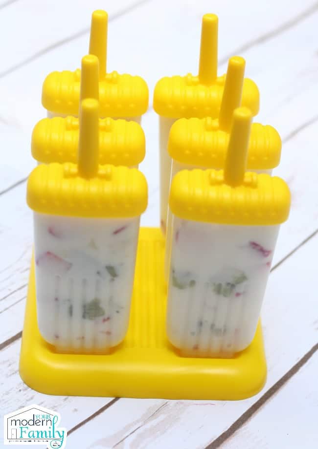 Frozen fruit and yogurt popcicles with yellow plastic holders.