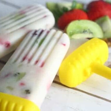 Homemade yogurt popsicles with a yellow plastic holder.