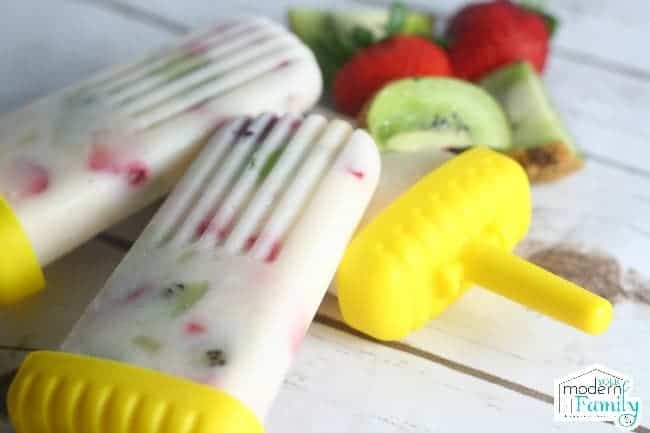 Homemade yogurt popsicles with a yellow plastic holder.