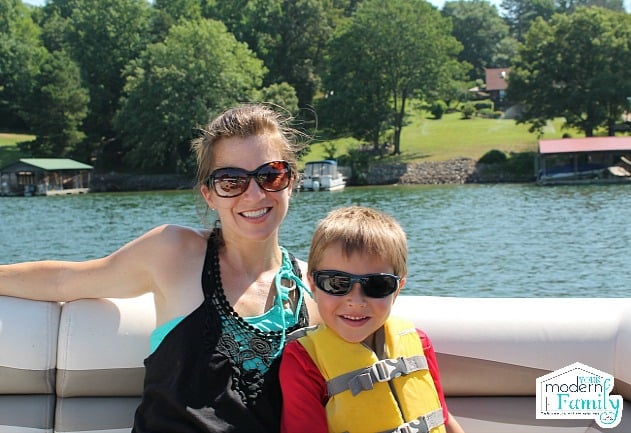 A woman and a little boy wearing sunglasses sitting on a boat.