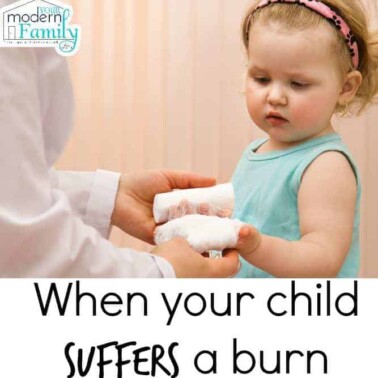 A person caring for a child with a burn on her hand.