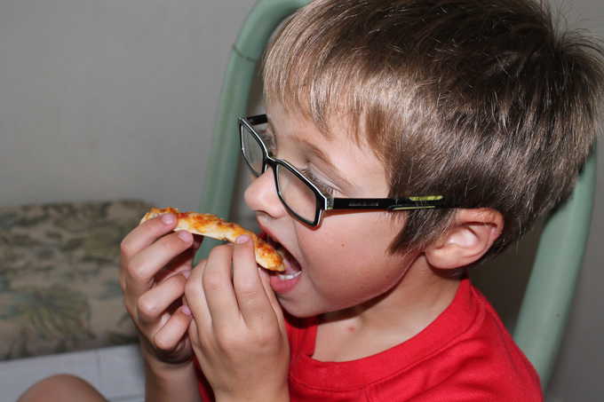 A young boy eating a slice of pizza.