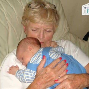 A baby lying on his grandma's shoulder.