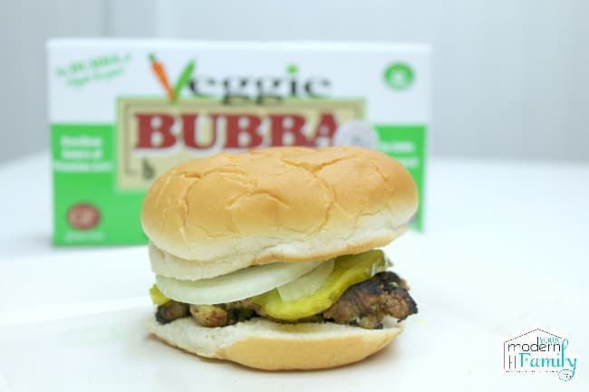 A hamburger on a white table with a box of Veggie Bubba Burgers in the background.