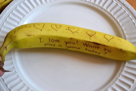 A banana sitting on top of a paper plate with text written on the peel.