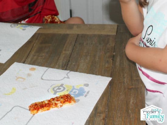 Children sitting at a table eating pizza.