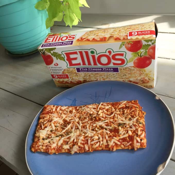 A serving of Ellio\'s pizza on a blue plate with a box of Ellio\'s behind it.