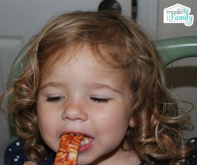 A little girl eating a slice of pizza.