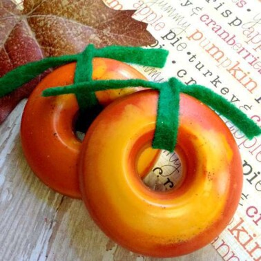 Two small brown donut shaped decorations with green felt ribbon tied at the top.