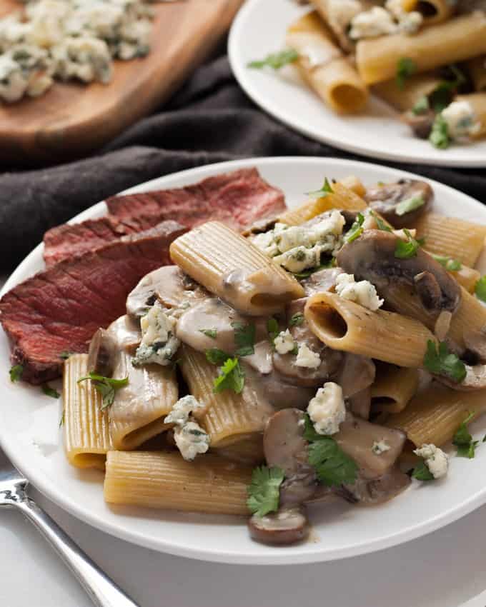 A plate of Mushroom blue cheese Rigatoni with a side of sliced beef.