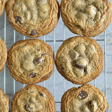 A batch of chocolate chip cookies resting on a wire rack.