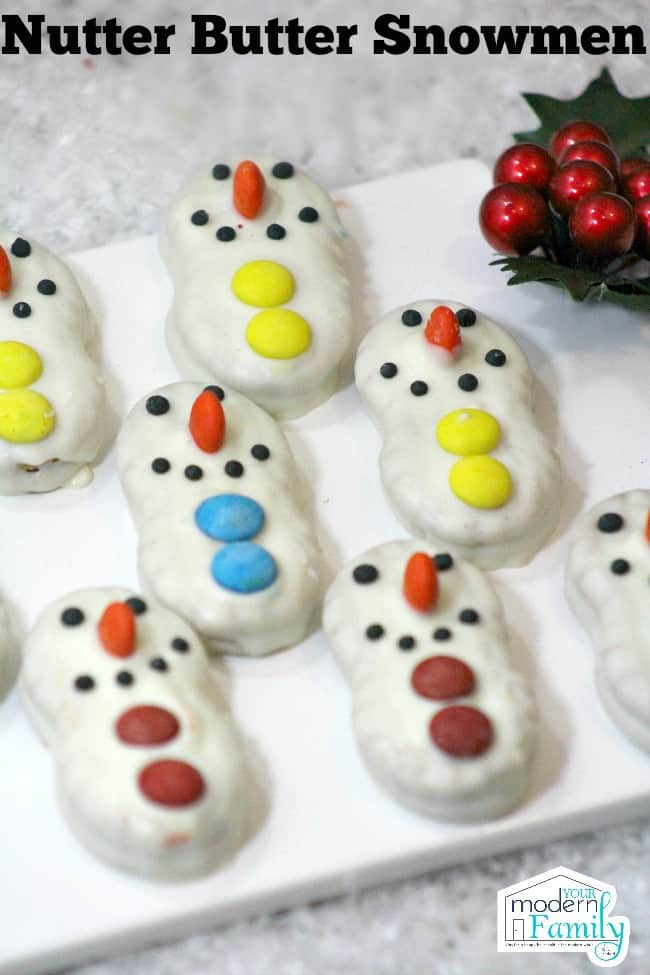 A tray filled with snowman decorated cookies with text above it.