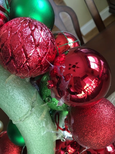 A close up of a Christmas wreath  with red ornaments on it.
