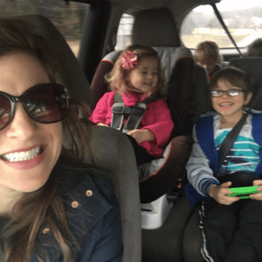 A group of people smiling while sitting in a van posing for the camera.